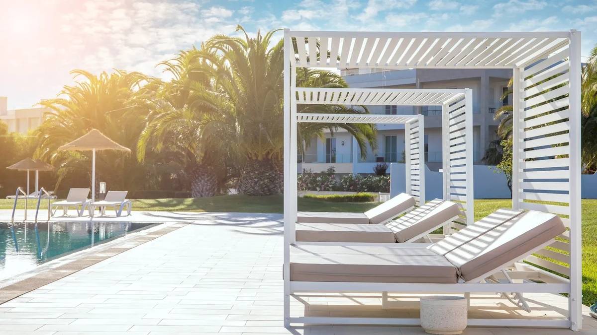 Pool-Loungebereich im Hotel Ancora Park mit weißen Sonnenliegen und Sonnenschirmen.
