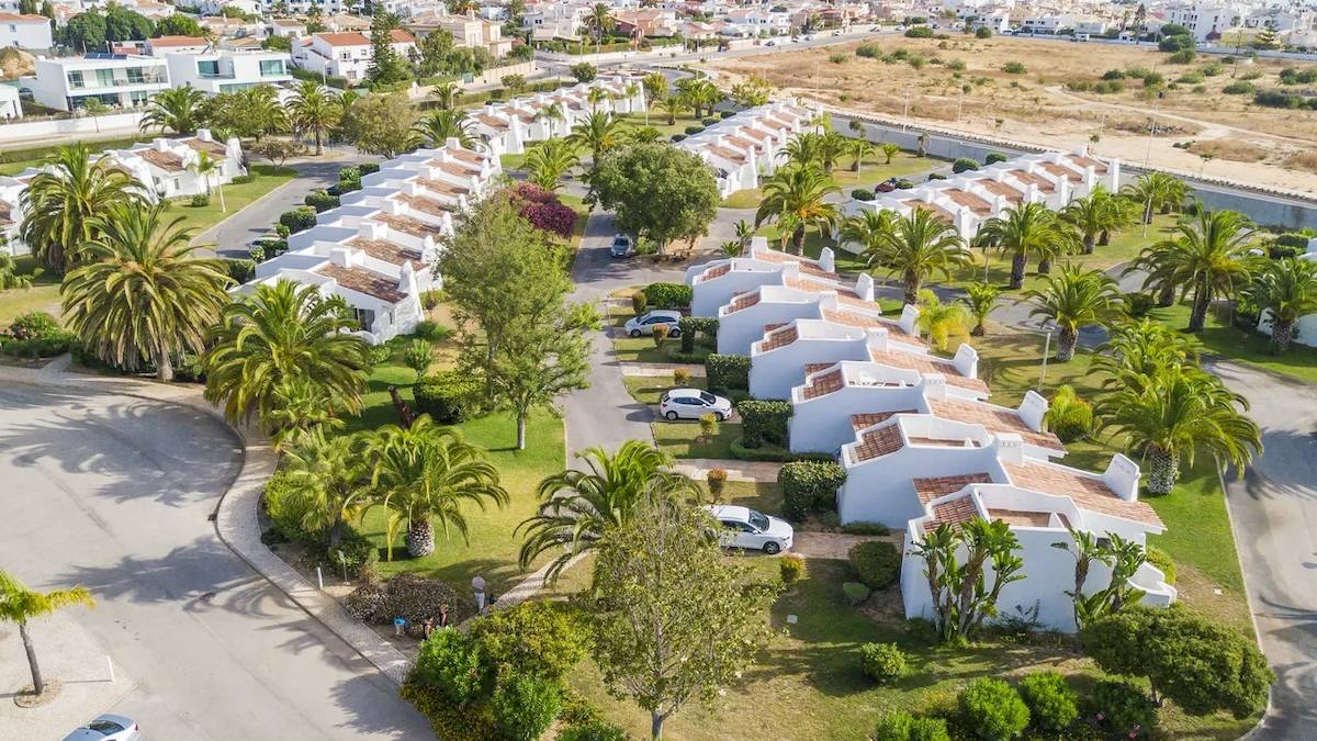 Luftaufnahme des Ancora Park Hotels mit mehreren weißen Reihenhäusern und geparkten Autos.