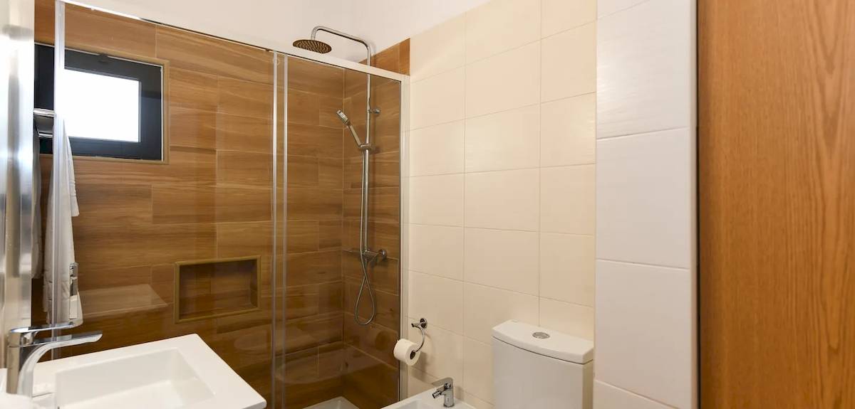Badezimmer im Pedras da Rainha Resort mit Dusche, Toilette und Waschbecken.