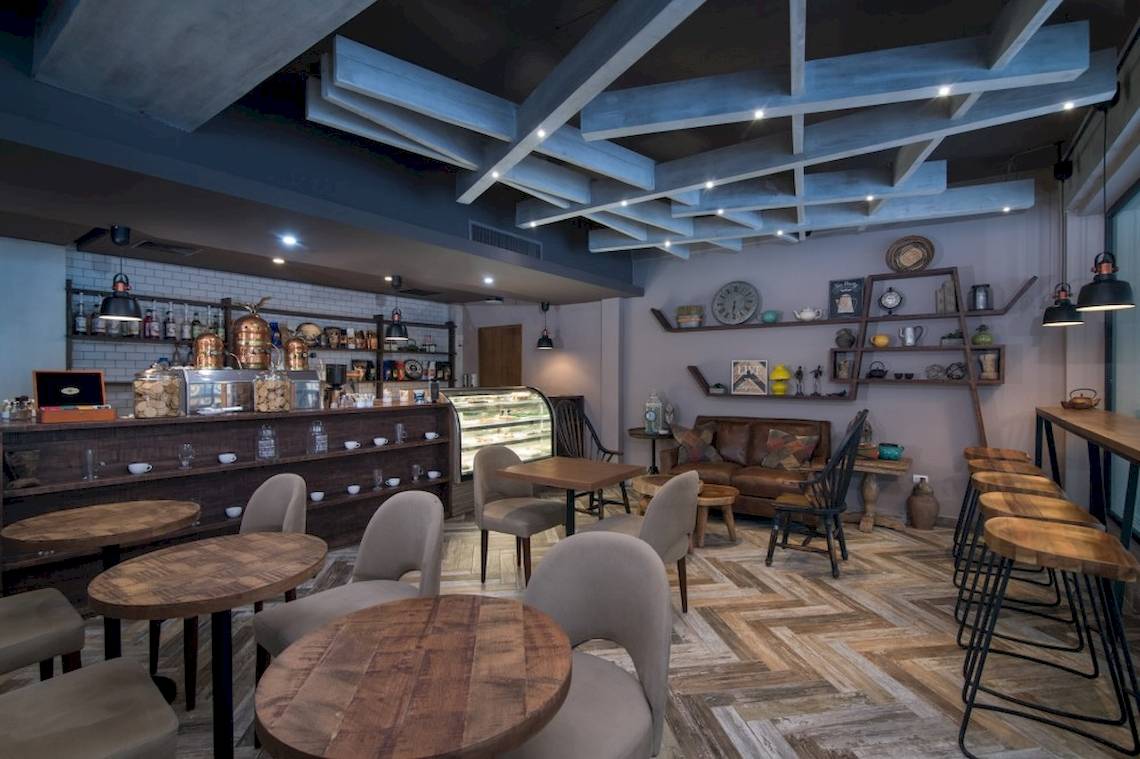 Innenbereich des Emotions By Hodelpa Puerto Plata Hotels mit Holztischen, Stühlen und einer Bar.