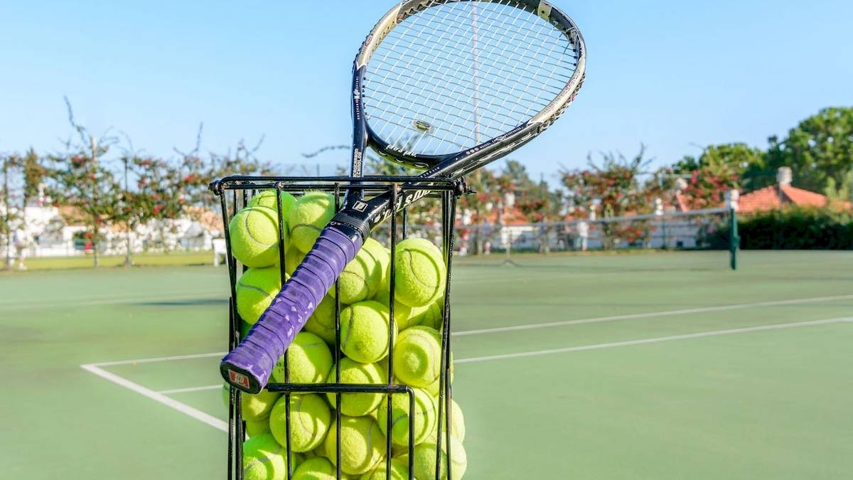 Korb voller Tennisbälle auf einem Tennisplatz im Freien