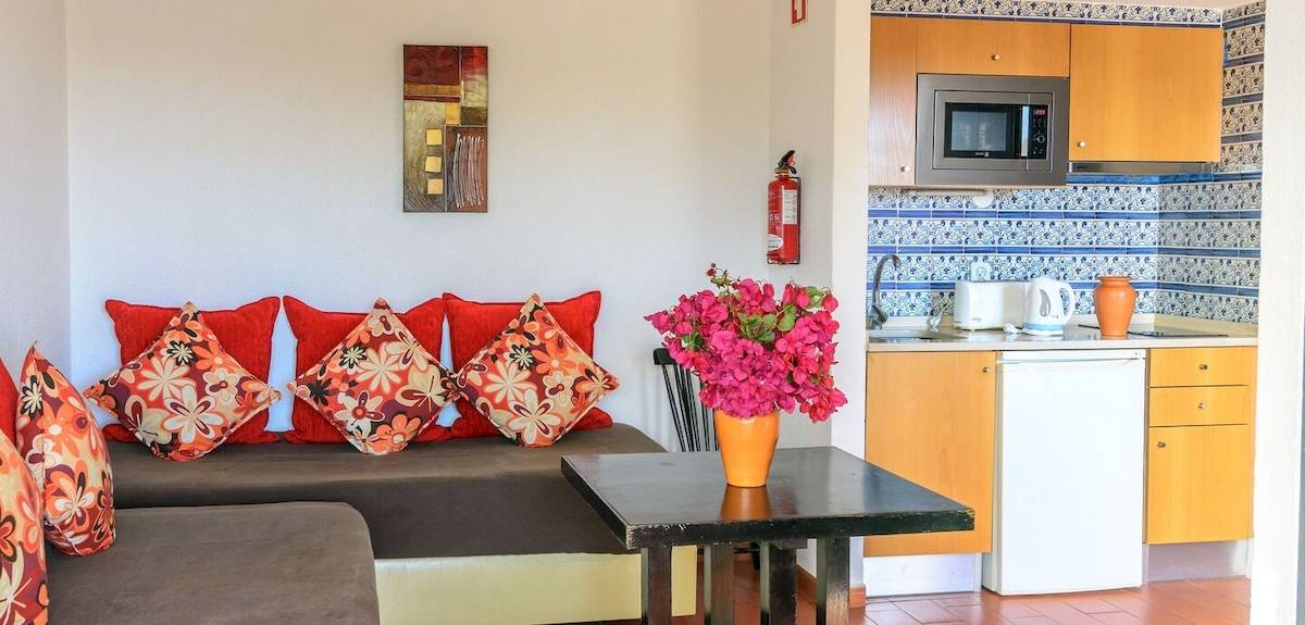 Inneneinrichtung des Pedras da Rainha Resorts mit Sofa, Tisch, Küche und Wanddekor.