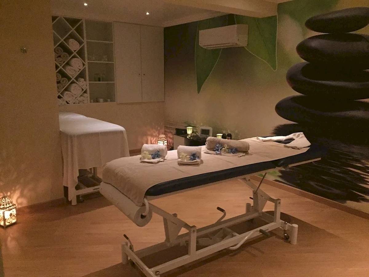Massageraum im Baia Grande Hotel mit Behandlungstisch, Liegen und steinigen Dekoration.