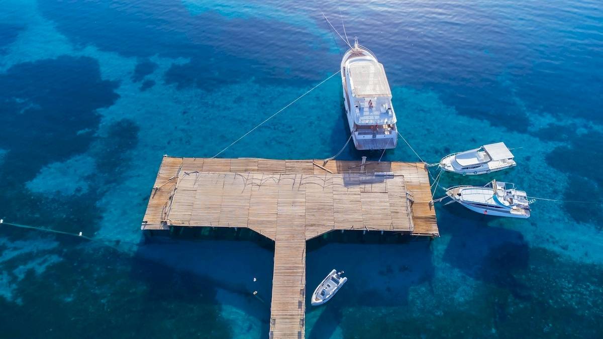 Luftaufnahme der Amwaj Beach Club Anlegestelle mit verankerten Booten im blauen Wasser