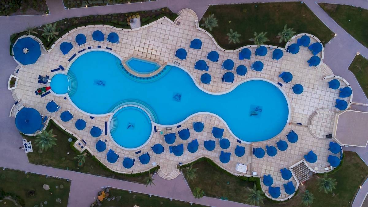 Oberflächenansicht des Amwaj Beach Club Pools mit blauen Sonnenschirmen und Wasser