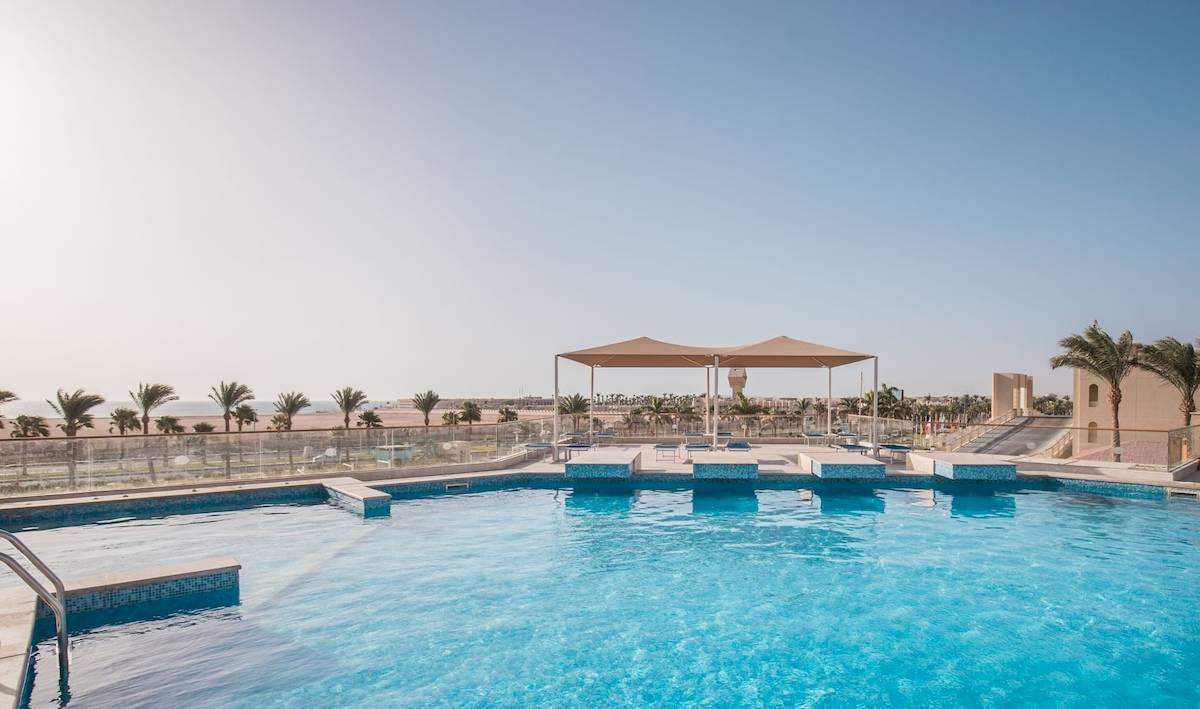 Außenpool des Pickalbatros Aqua Vista Resort mit Sonnenschirm und Blick auf Palmen und Meer.