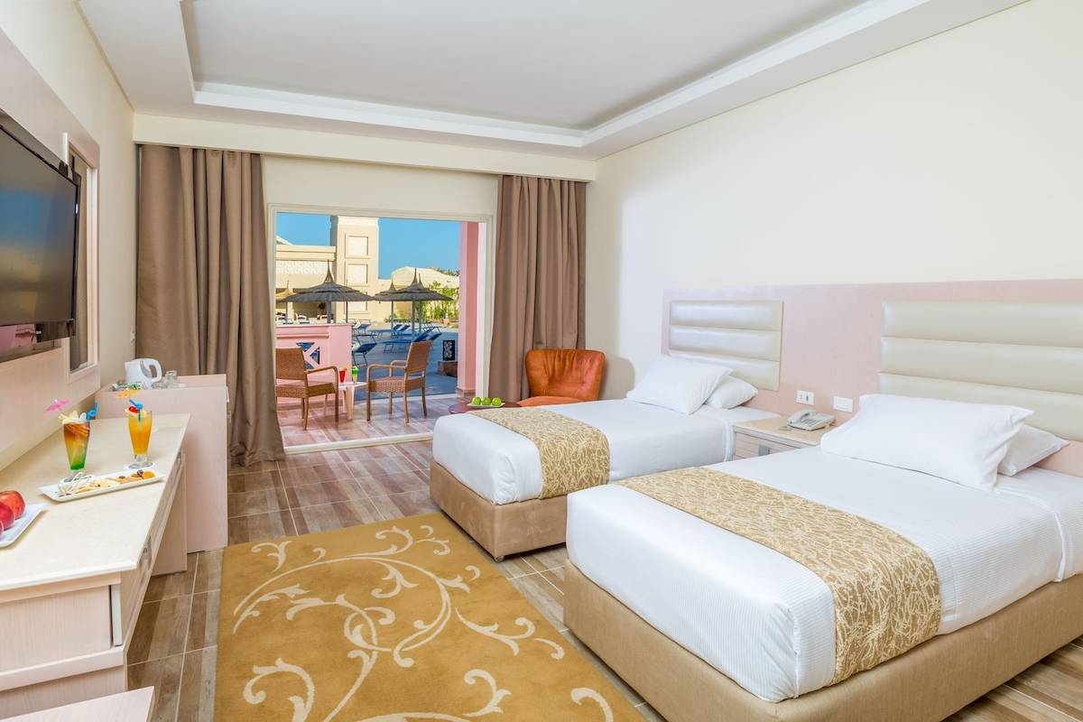 Doppelzimmer mit Balkon im Pickalbatros Aqua Vista Resort mit zwei Betten, einem Tisch und einem Fernseher.