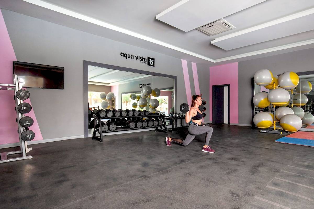 Frau trainiert im Fitnessstudio mit Gewichten und Medizinbällen