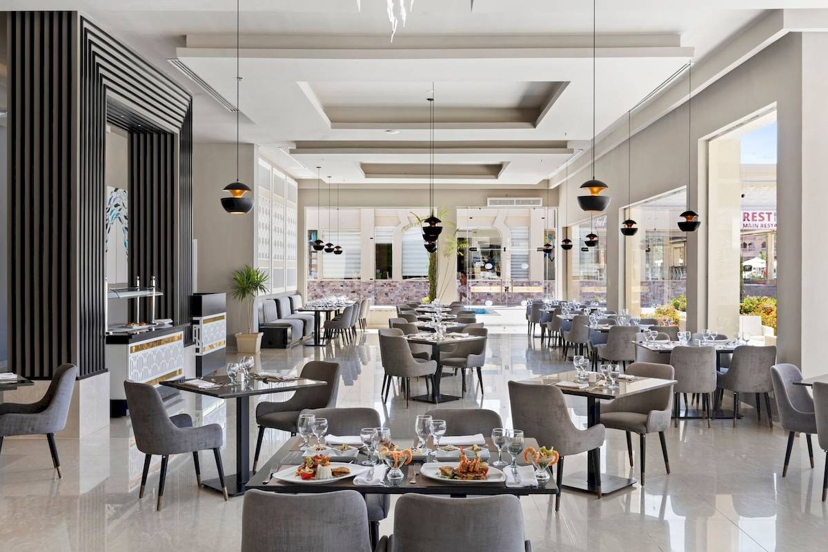 Innenansicht des Restaurants im Pickalbatros Aqua Vista Resort mit runden Tischen, Stühlen und Speisentellern.