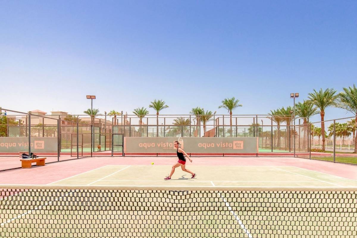 Tennisplatz im Pickalbatros Aqua Vista Resort mit einer Spielerin, die den Ball schlägt.
