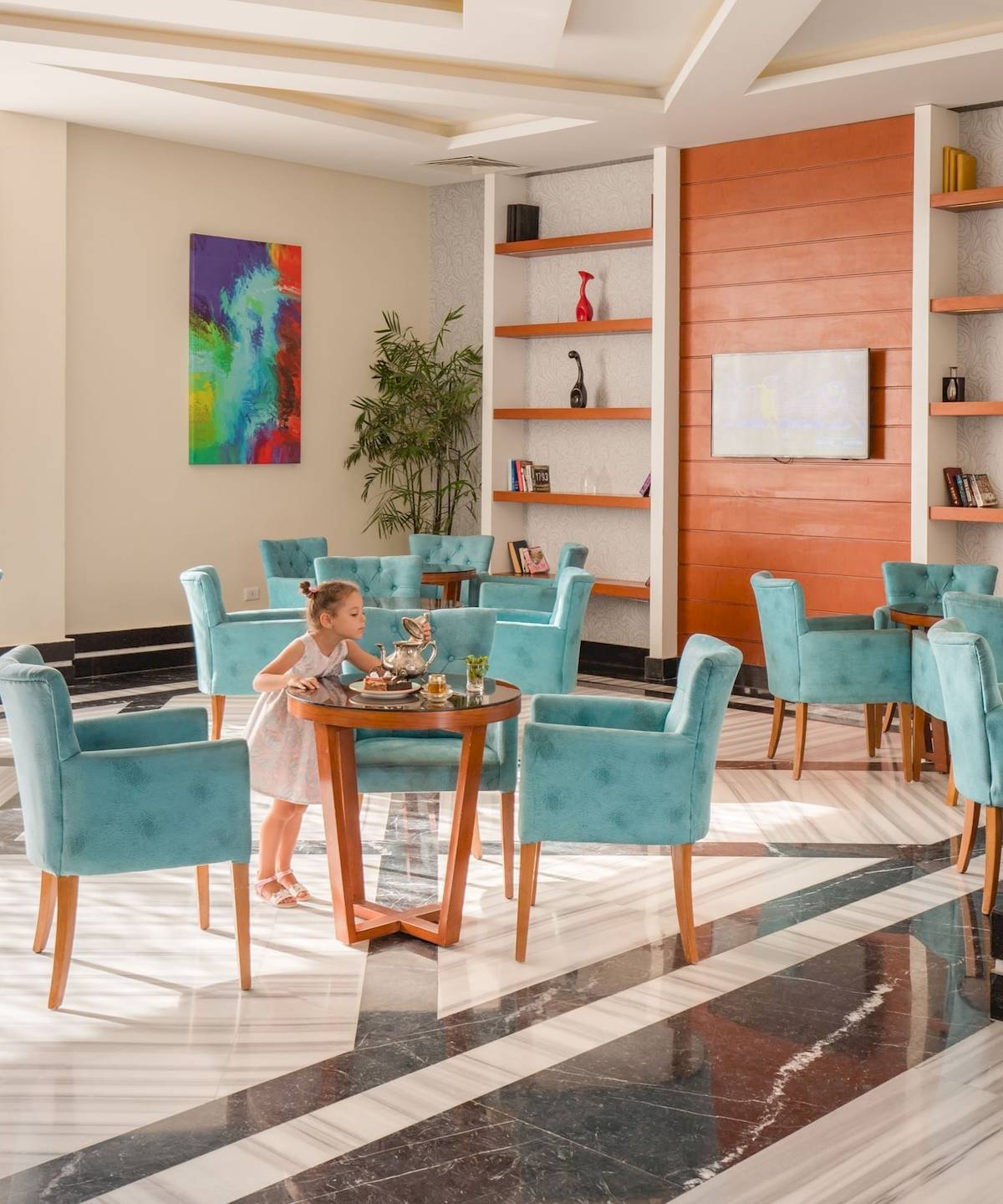 Ein Mädchen sitzt in einem blauen Stuhl in der Lobby des Pickalbatros Aqua Vista Resort Hotels.