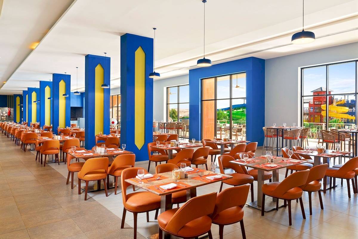 Restaurant im Pickalbatros Water Valley Resort by Neverland mit blauen und gelben Säulen und Tischen im Freien.