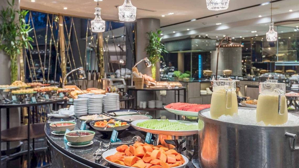 Frühstücksbuffet im Chatrium Hotel Riverside Bangkok mit verschiedenen Gerichten und Früchten.