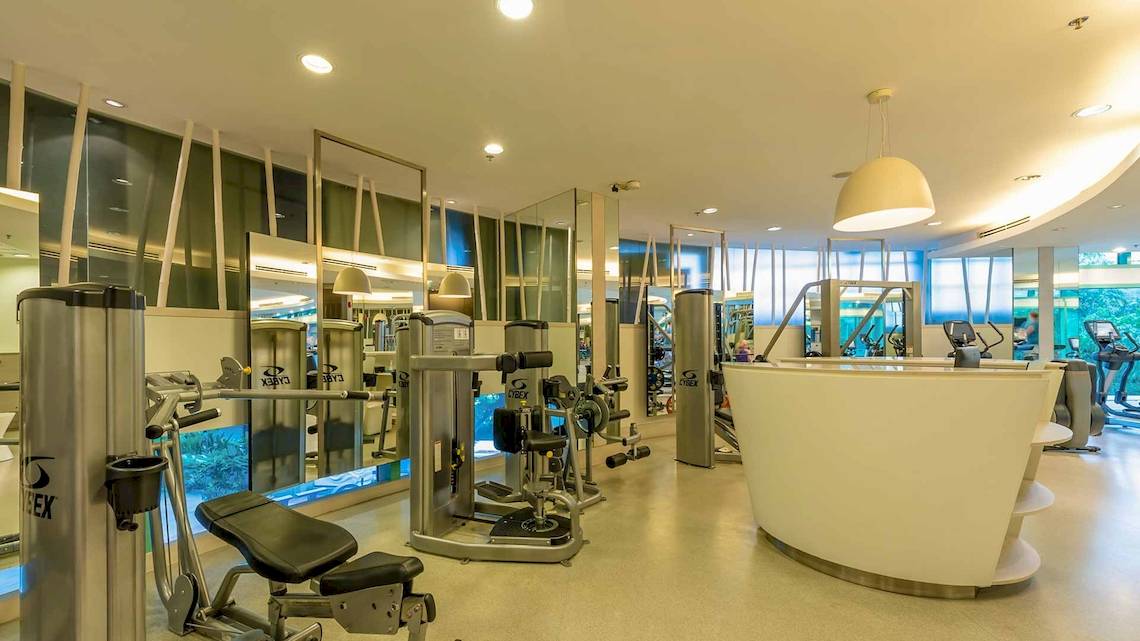 Fitnesscenter im Chatrium Hotel Riverside Bangkok mit verschiedenen Trainingsgeräten und einer Theke.