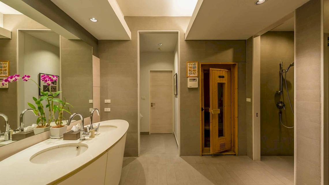 Das Badezimmer im Chatrium Hotel Riverside Bangkok mit zwei Waschbecken, Spiegel und einem offenen Saunaraum.