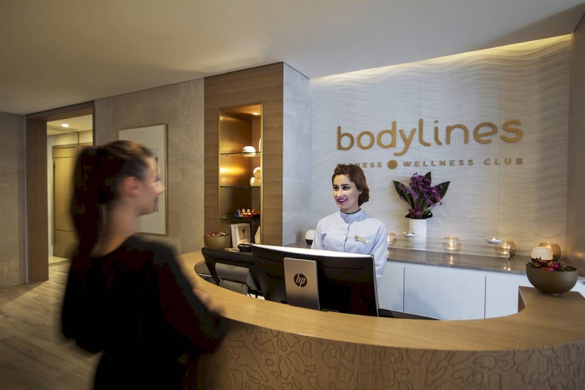 Rezeptionistin im Bodylines Wellness Club, eine Frau lächelt und bedient den Computer