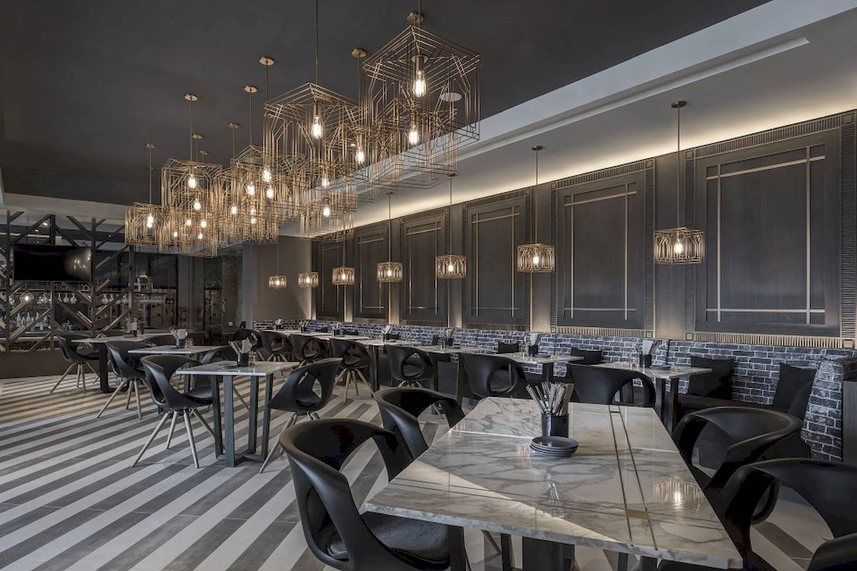 Innenansicht des Al Bandar Rotana Hotel Restaurants mit modernen Möbeln und goldenen Kronleuchtern.