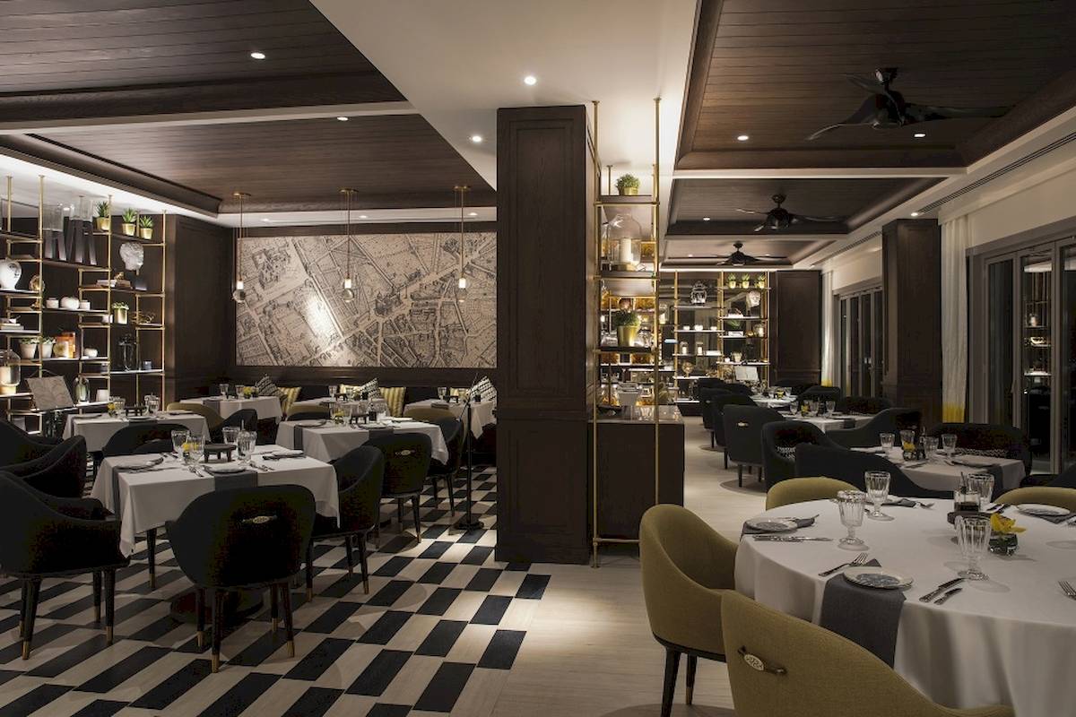 Innenansicht des Al Bandar Rotana Hotel Restaurants mit geschwungenen Möbeln und gemusterten Böden.