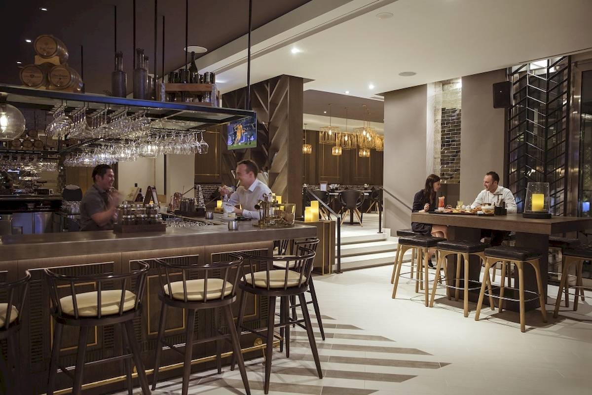 Hotelbar im Al Bandar Rotana mit Gästen an der Bar und Tischen.