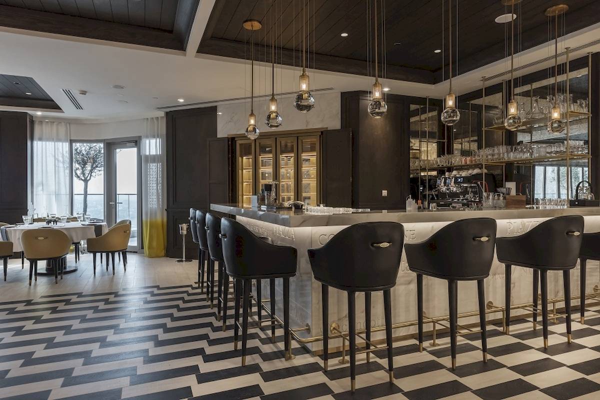 Innenansicht der Bar im Al Bandar Rotana Hotel mit schwarzen und weißen Sesselreihen und Marmortheke.