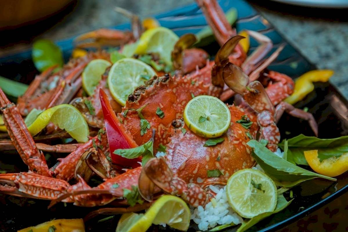 Ein Gericht mit gegrillten Krabben auf Reis serviert, garniert mit Limettenscheiben und grünem Blattwerk.