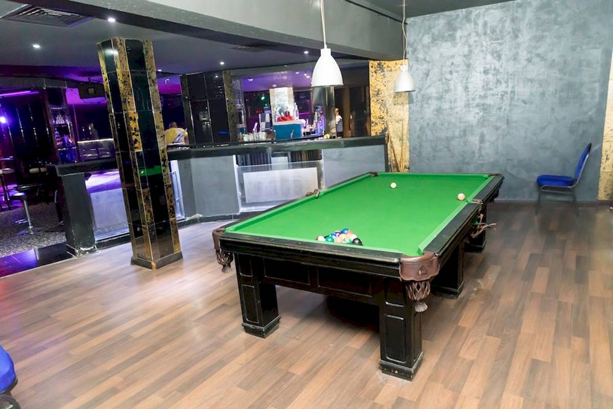 Ein Pooltisch in einer Bar mit grünem Tisch und blauen Bänken.