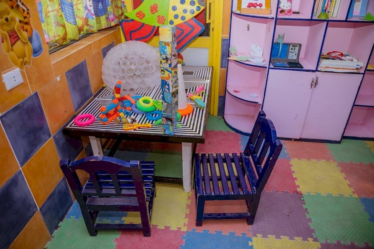 Ein Kinderzimmer mit bunten Wänden, Spieltischen und Spielzeug.