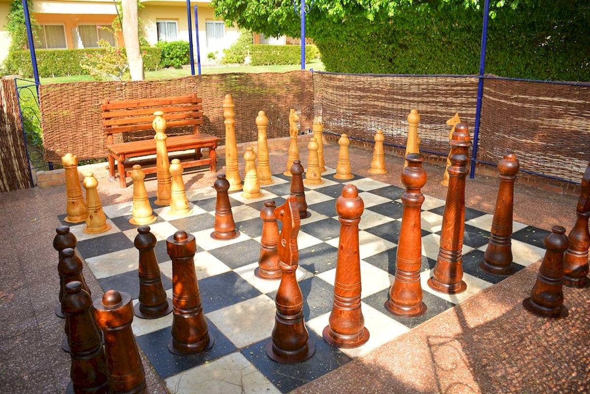 Großes Schachspiel im Garten des Golden Beach Resort mit hölzernem Schachbrett und Figuren.