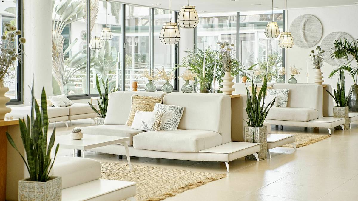 Lobby des Iberostar Cristina Hotels mit weißen Möbeln, Pflanzen und großen Fenstern.