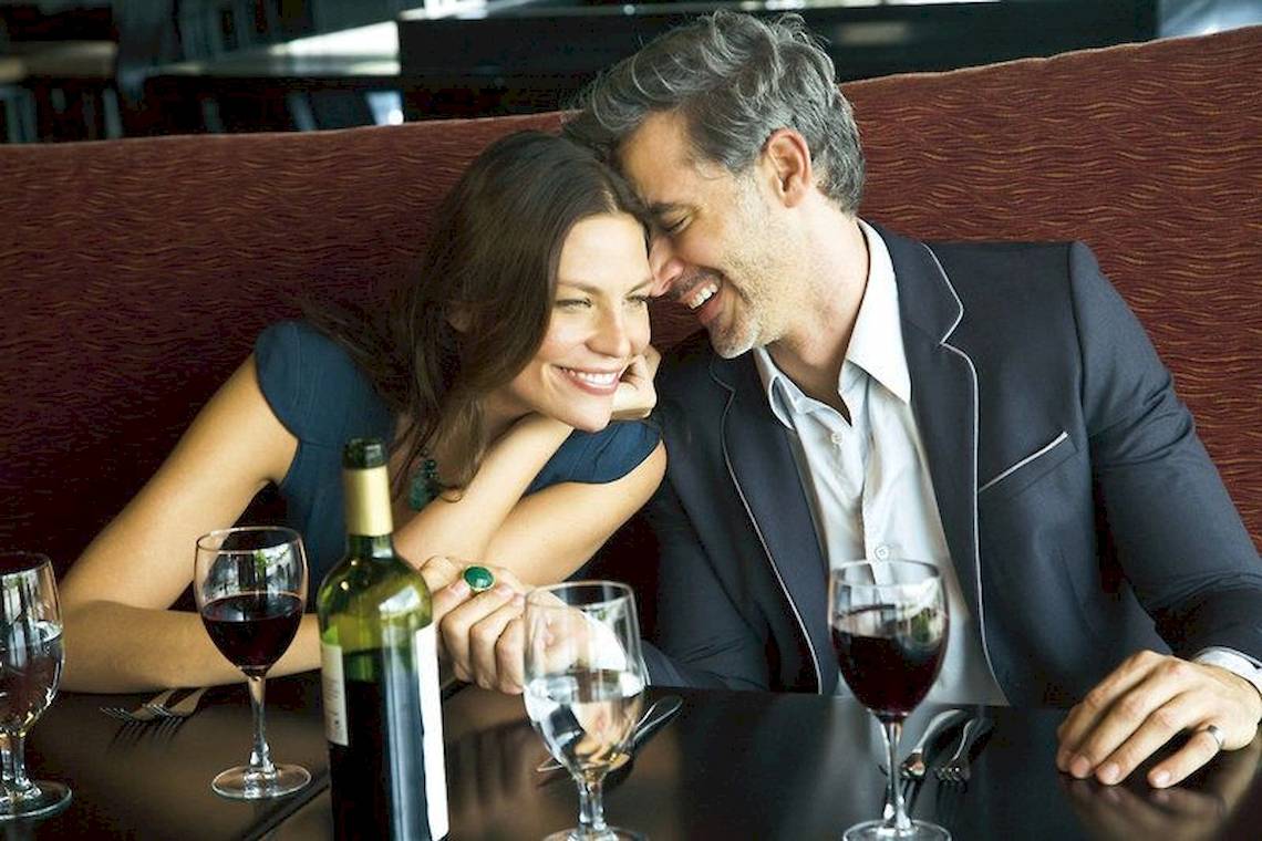 Paar im Restaurant mit Wein, das lächelt und genießt den Moment.
