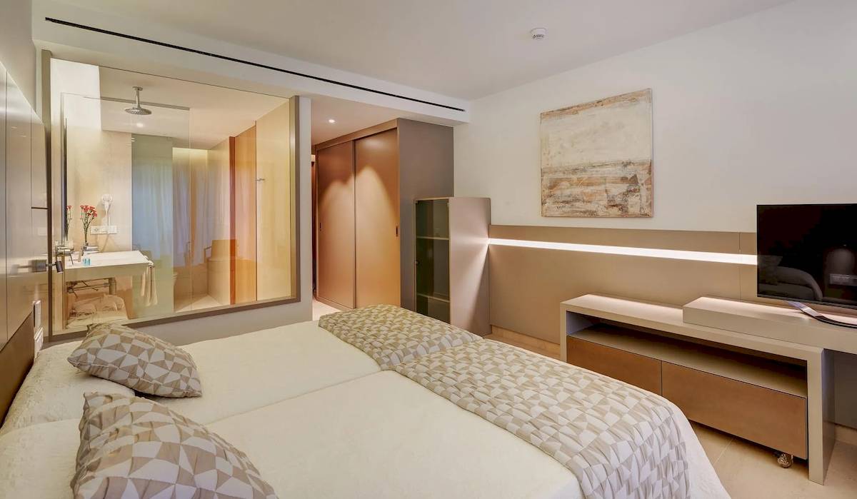 Schlafzimmer im Hipotels Gran Playa de Palma Hotel mit zwei Betten, Fernseher und Glaswand.
