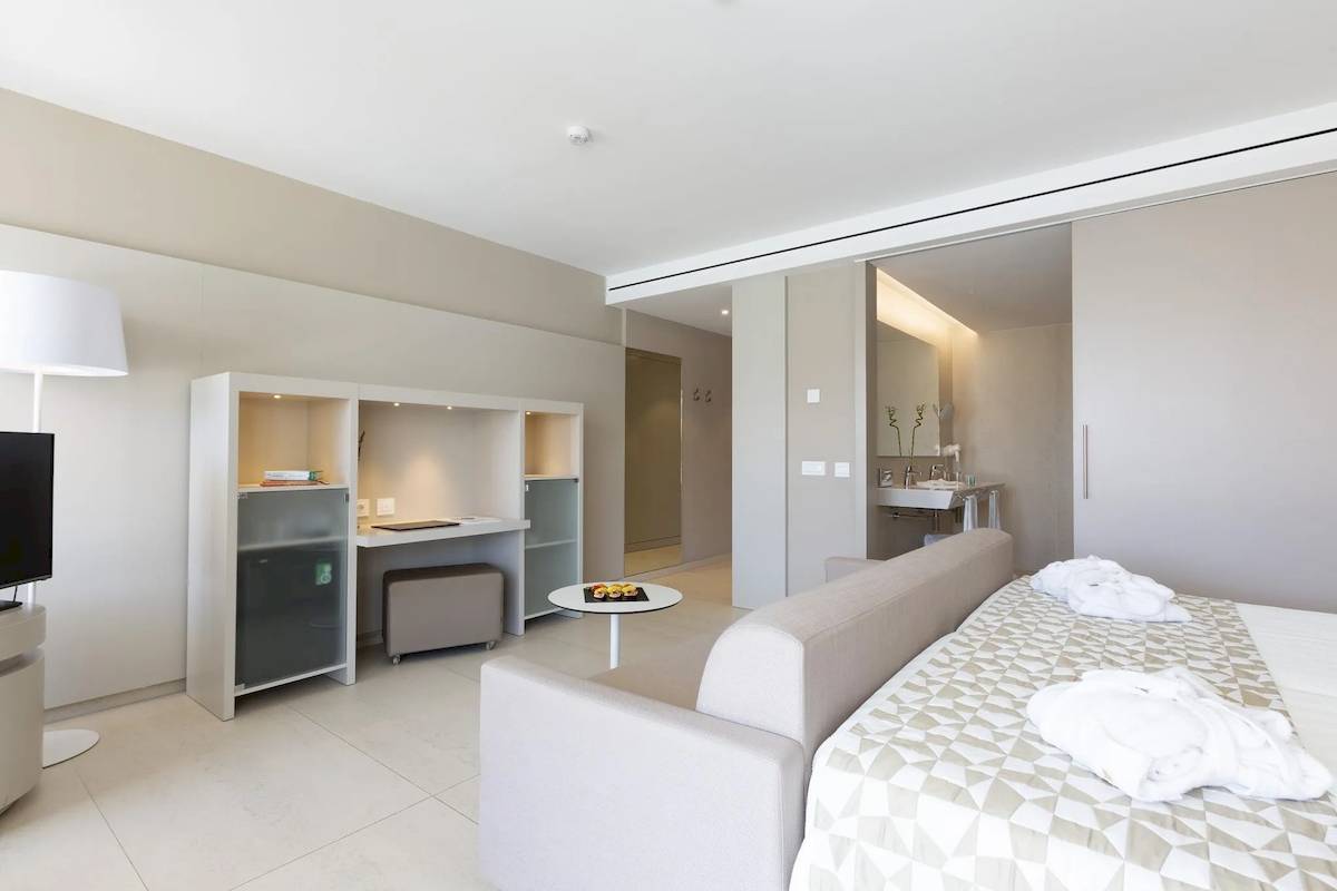 Innenansicht der Suite im Hipotels Gran Playa de Palma mit Bett, Sofa, Schreibtisch und Bad.
