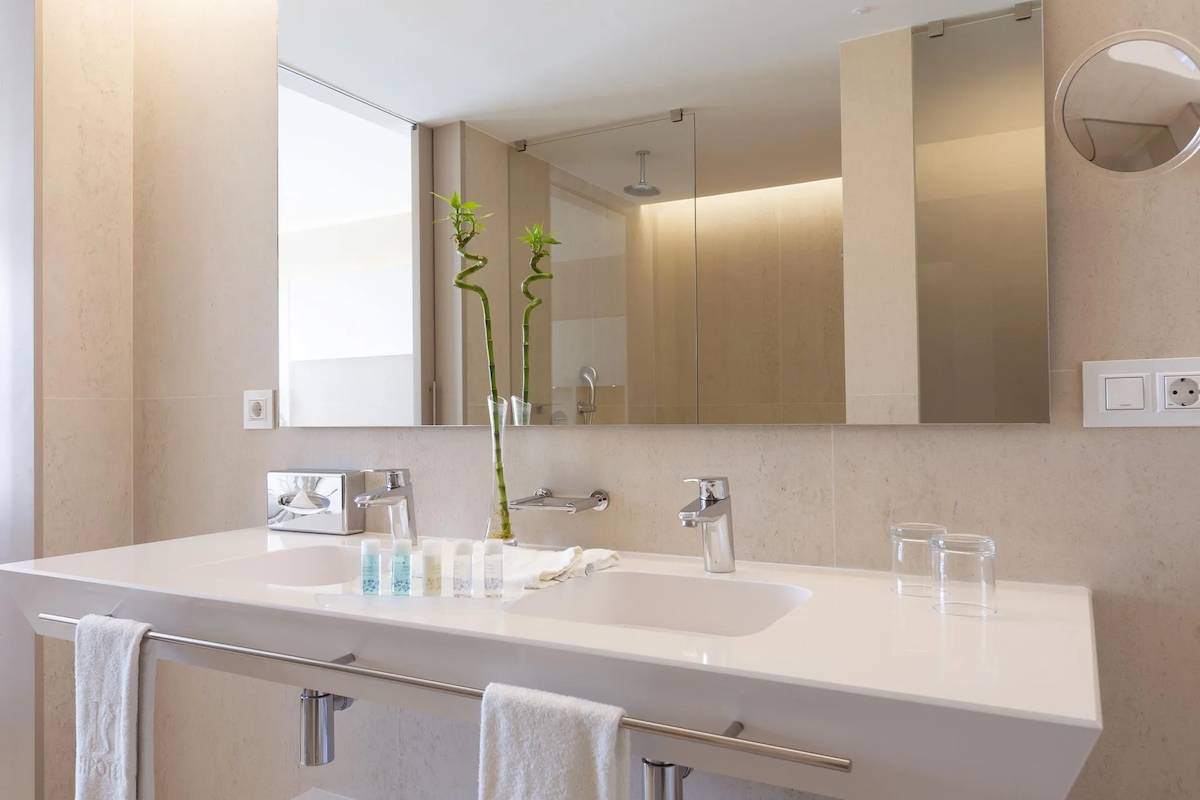 Badezimmer im Hipotels Gran Playa de Palma mit zwei Waschbecken, Spiegeln und Handtüchern.