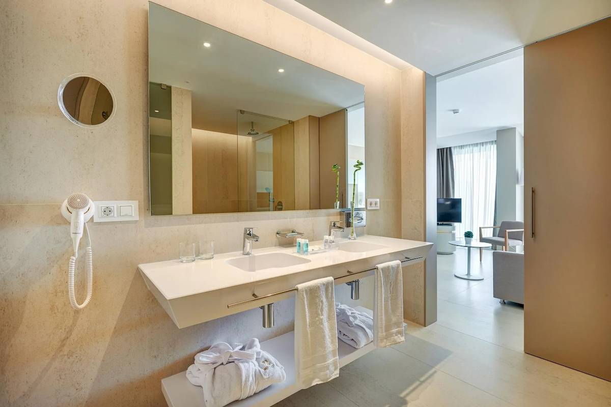 Badezimmer im Hipotels Gran Playa de Palma mit Doppelwaschbecken, Spiegel und Handtüchern.