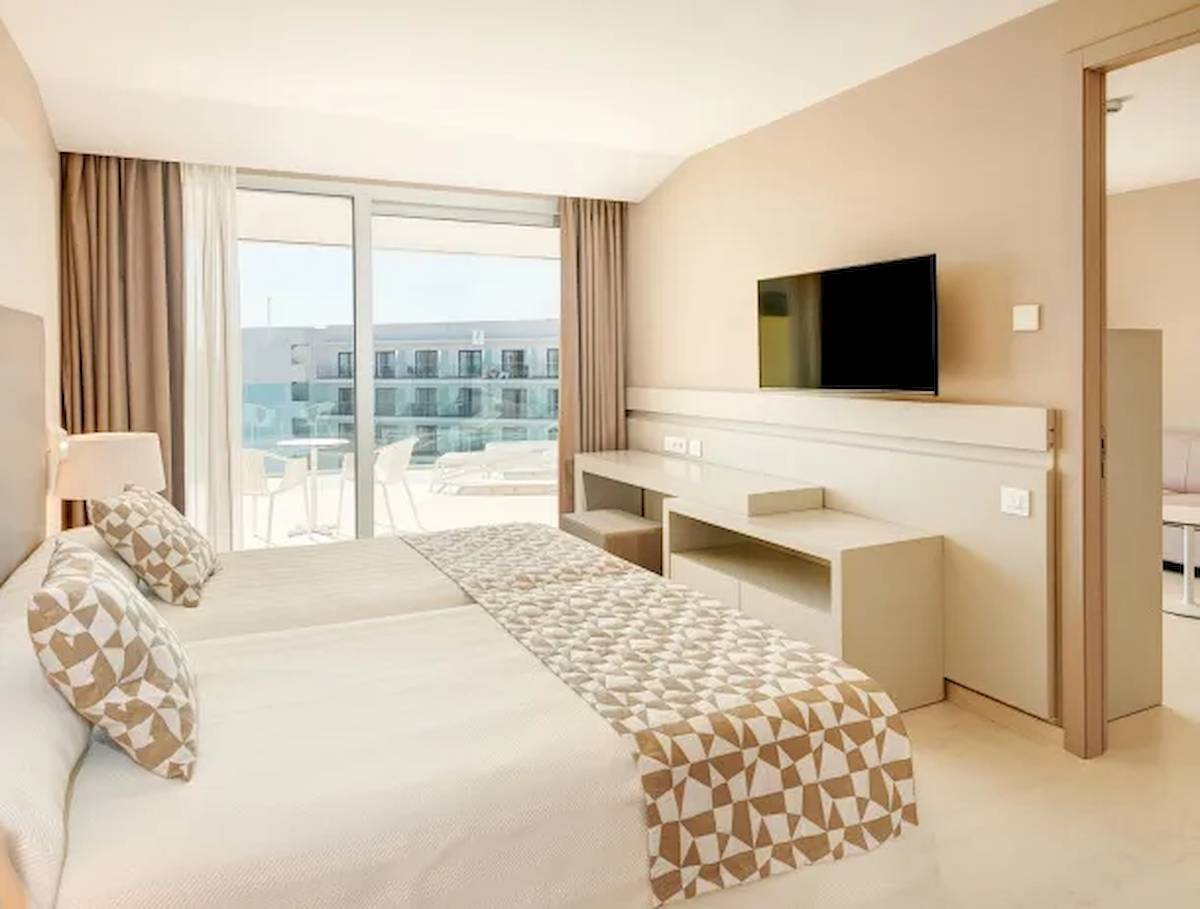 Ein Hotelzimmer mit Doppelbett, Fernseher, Schreibtisch und Meerblick.