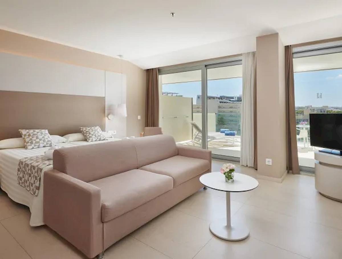 Suite Zimmer im Hipotels Gran Playa de Palma mit Bett, Sofa, Tisch und Fernseher.