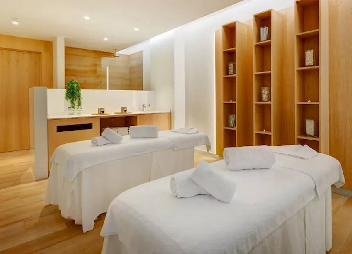Wellness-Bereich im Hipotels Gran Playa de Palma mit zwei weißen Massagetischen und Holzschränken.
