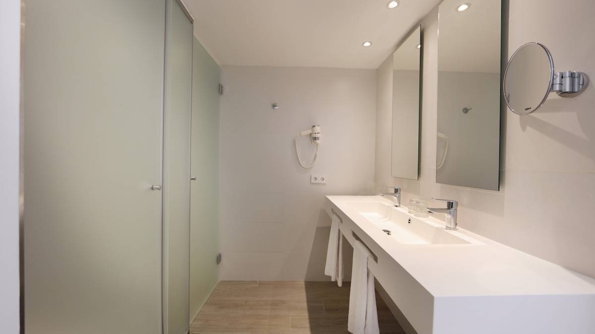 Badezimmer im Iberostar Playa de Muro mit Dusche, Spiegeln und Waschbecken.