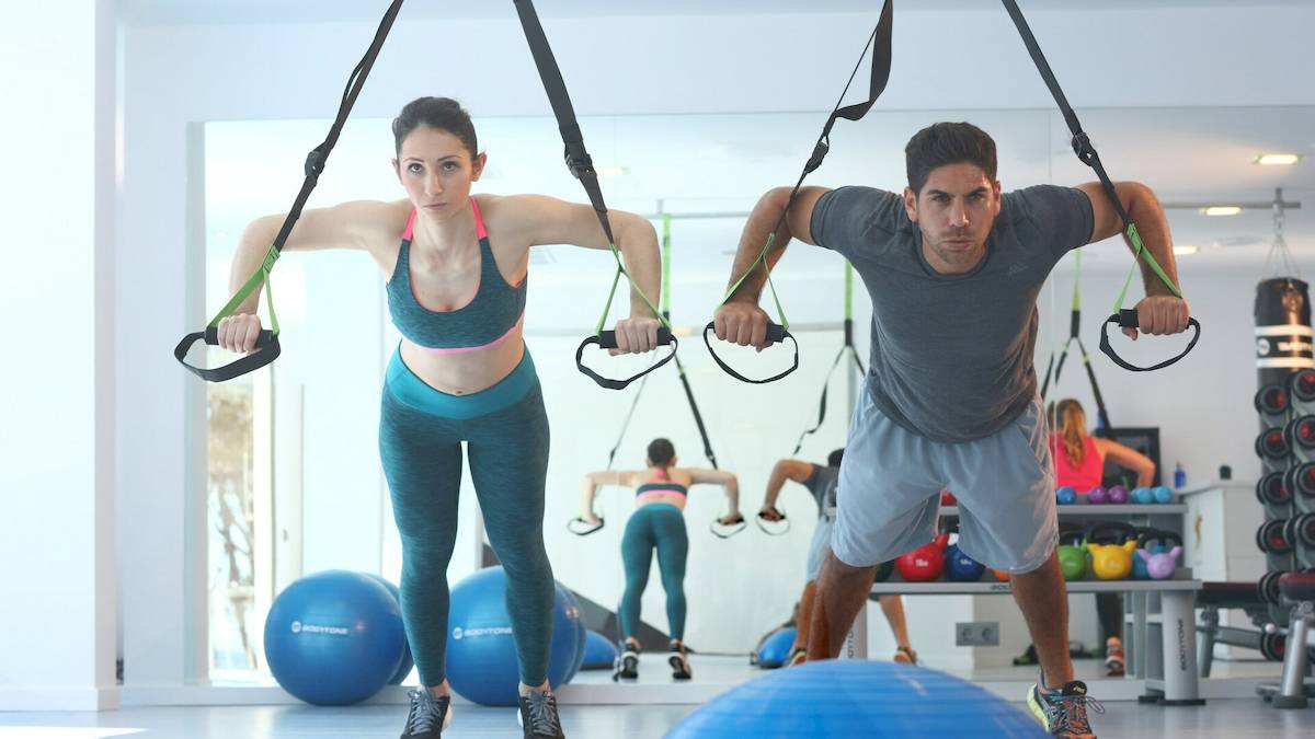 Fitness Workout im Hotel Iberostar Playa de Muro mit einer Frau und einem Mann, die an Zugbändern ziehen.