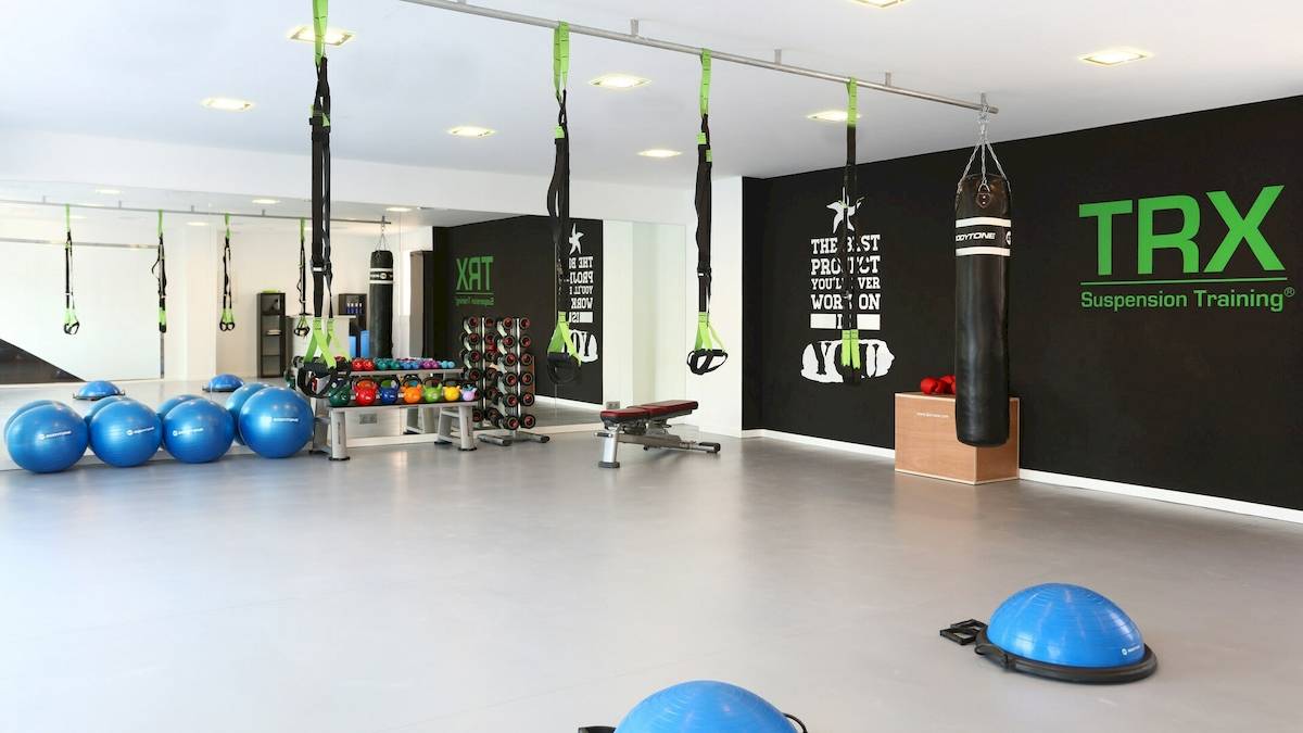 Fitnessstudio im Iberostar Playa de Muro Hotel mit TRX-Trainingsgeräten und Hanteln.