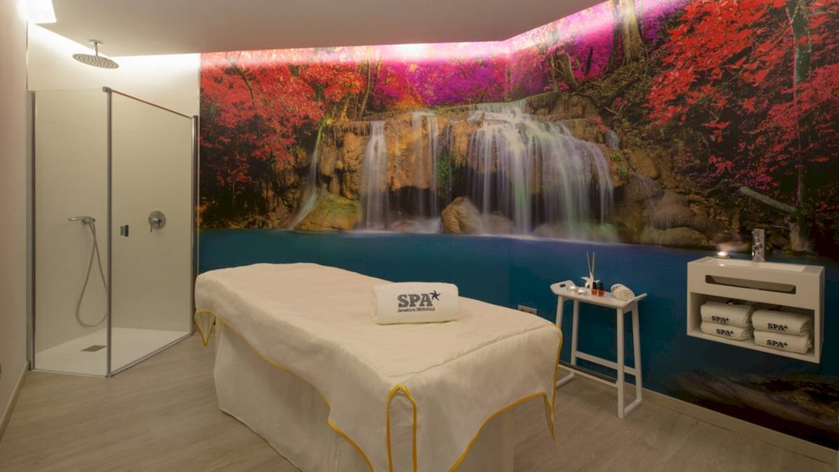 SPA-Behandlungsraum im Iberostar Playa de Muro Hotel mit Wasserfall-Wandbild und Behandlungstisch.