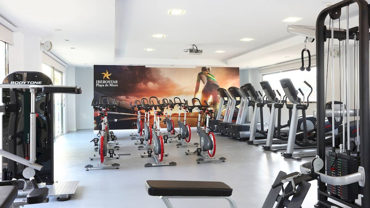 Fitnessstudio im Iberostar Playa de Muro mit einer Reihe von Spinrädern und Laufbändern.