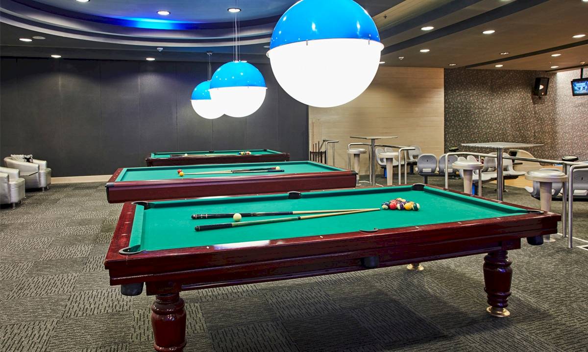 Zwei Billardtische im Hotellobby des Gloria Serenity Resort mit blauen Leuchten an der Decke.