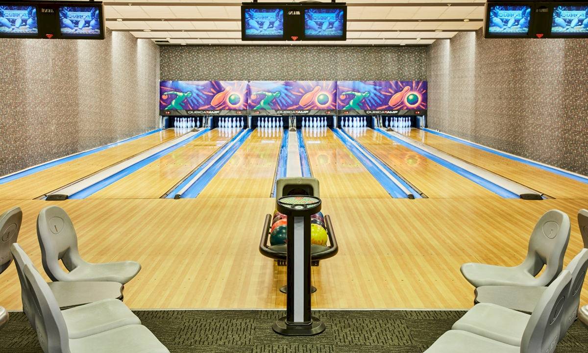 Bowlinghalle des Gloria Serenity Resort mit Bowlingbahnen, Monitoren und leeren Sitzen.