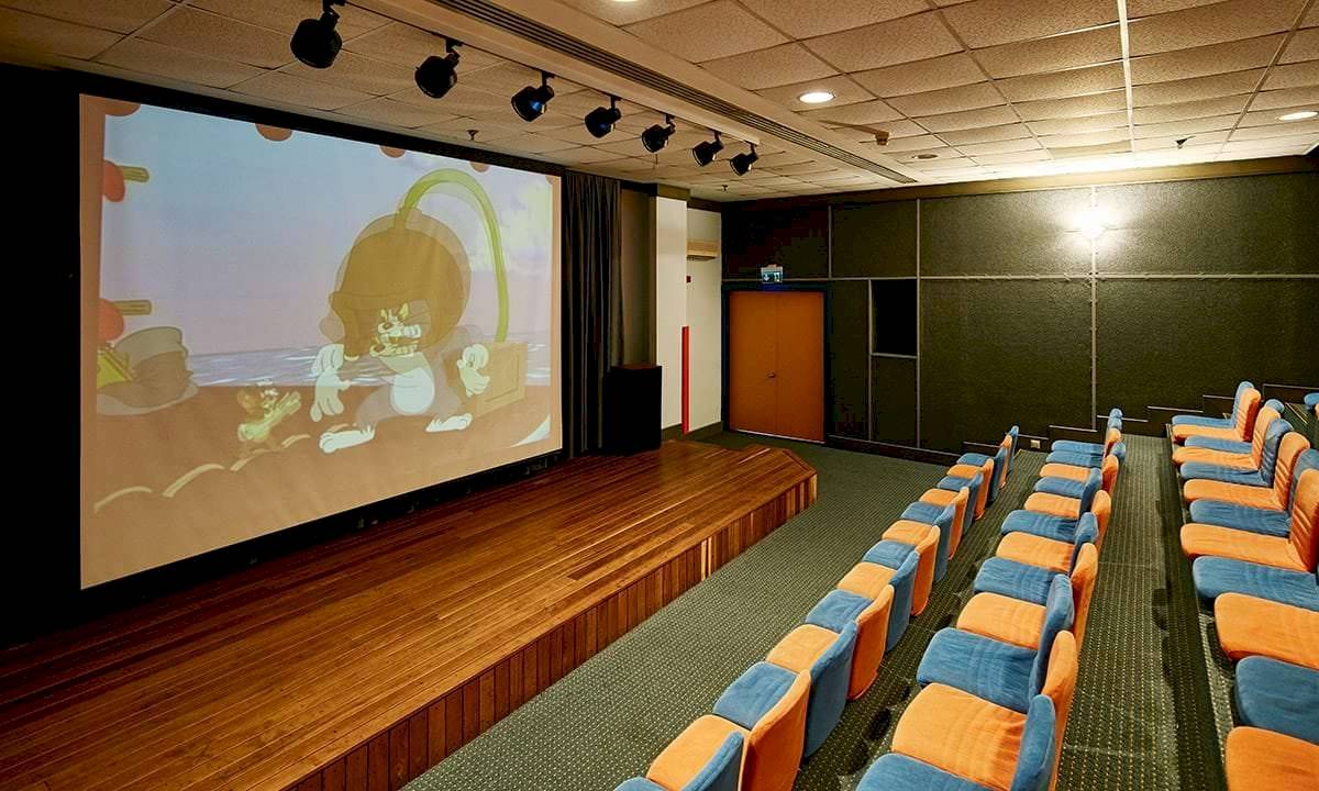 Kinosaal im Gloria Golf Resort mit leeren Bänken und laufendem Film auf der Leinwand.
