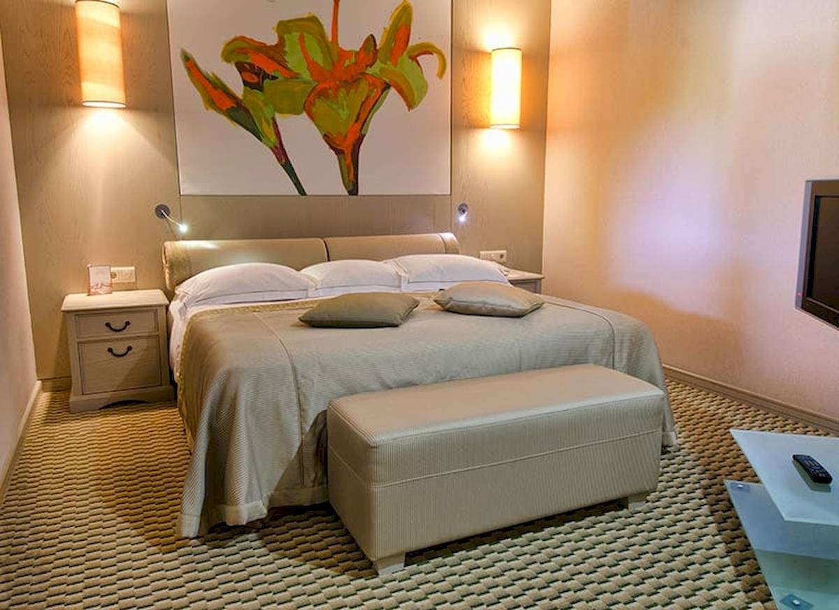Schlafzimmer im Gloria Golf Resort Hotel mit großem Bett, Nachttischen und Fernseher.