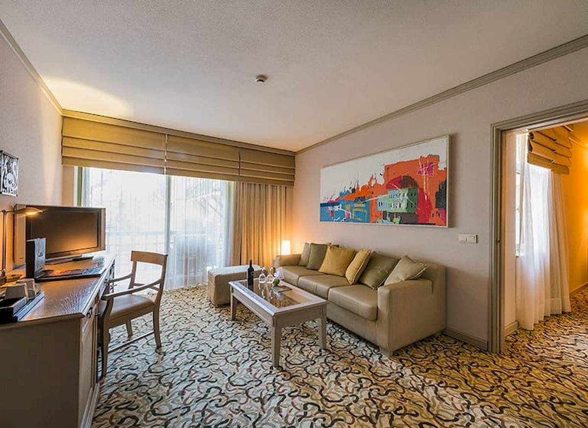 Wohnbereich der Suite im Gloria Golf Resort mit Couch, Schreibtisch und Fernseher.