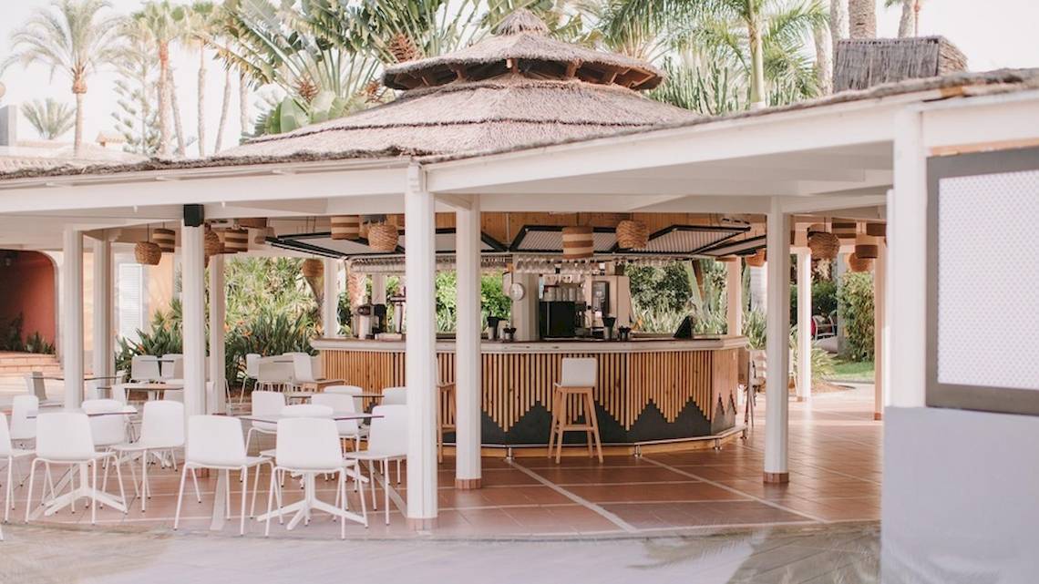 Barbereich des Suites & Villas By Dunas Hotels mit runden Tischen und Stühlen.