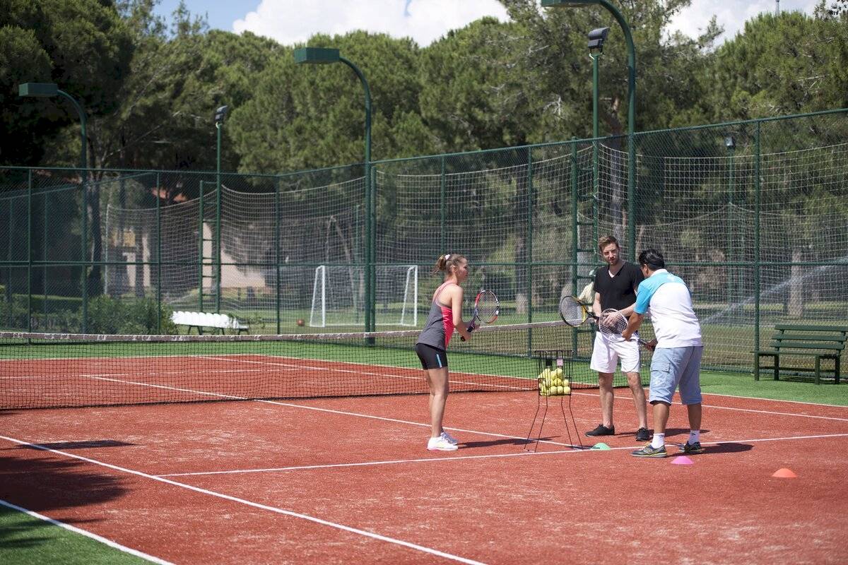 Tennistraining auf einem Platz im Xanadu Resort Hotel mit einer Frau und zwei Männern.