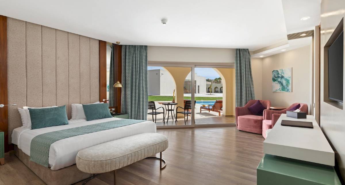Innenansicht eines Hotelzimmers im Xanadu Makadi Bay mit Doppelbett, Sitzbereich und Terrassentür.